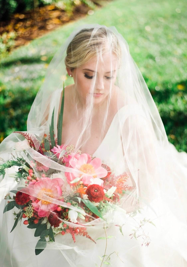 sheer drop wedding veil over updo with V neckline gown and pink bouquet