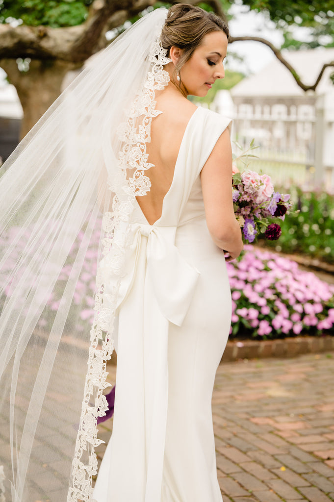 winding vine and leaf rose edged long wedding veil on bride with wildflower pink and purple bouquet
