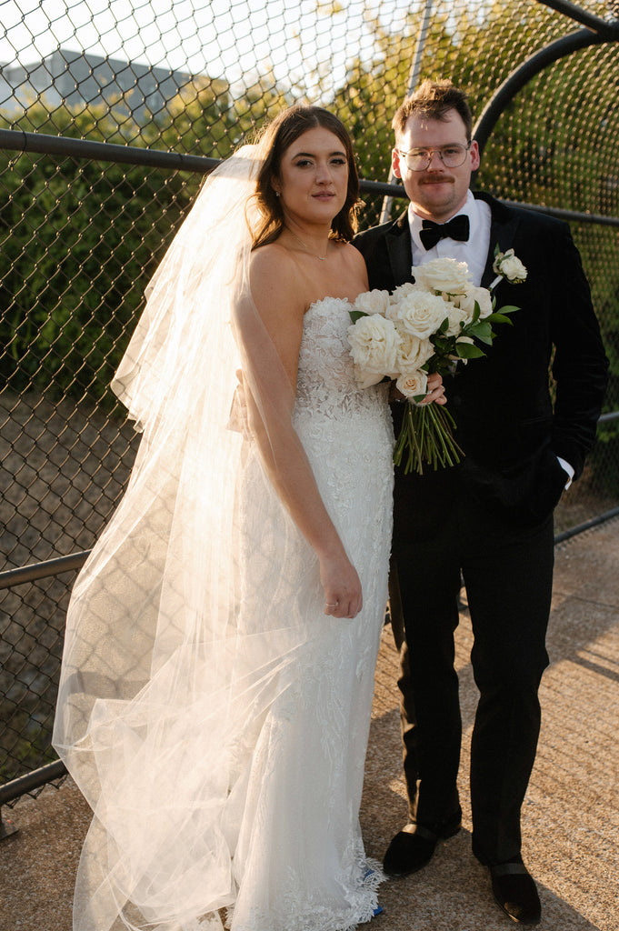 extra full wedding veil chapel length on bride holding white bouquet on bridge