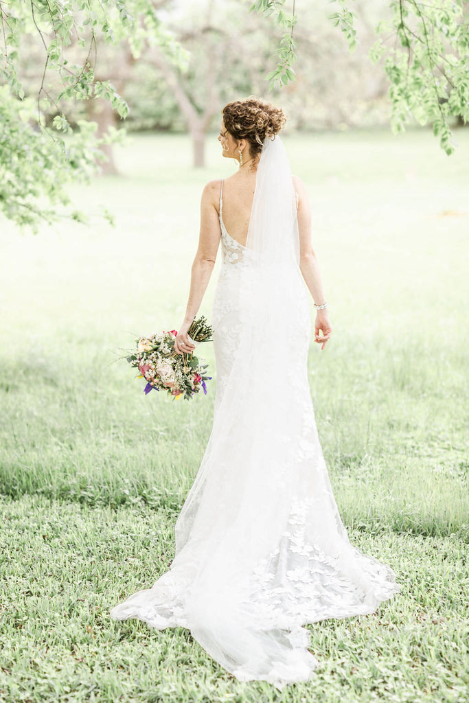 curly updo mid level bun with lace trimmed cathedral bridal veil
