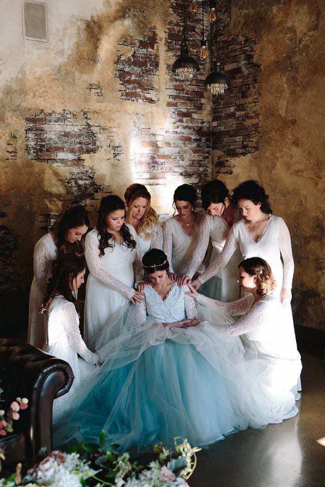 praying over bride in blue wedding dress before she walks down the aisle