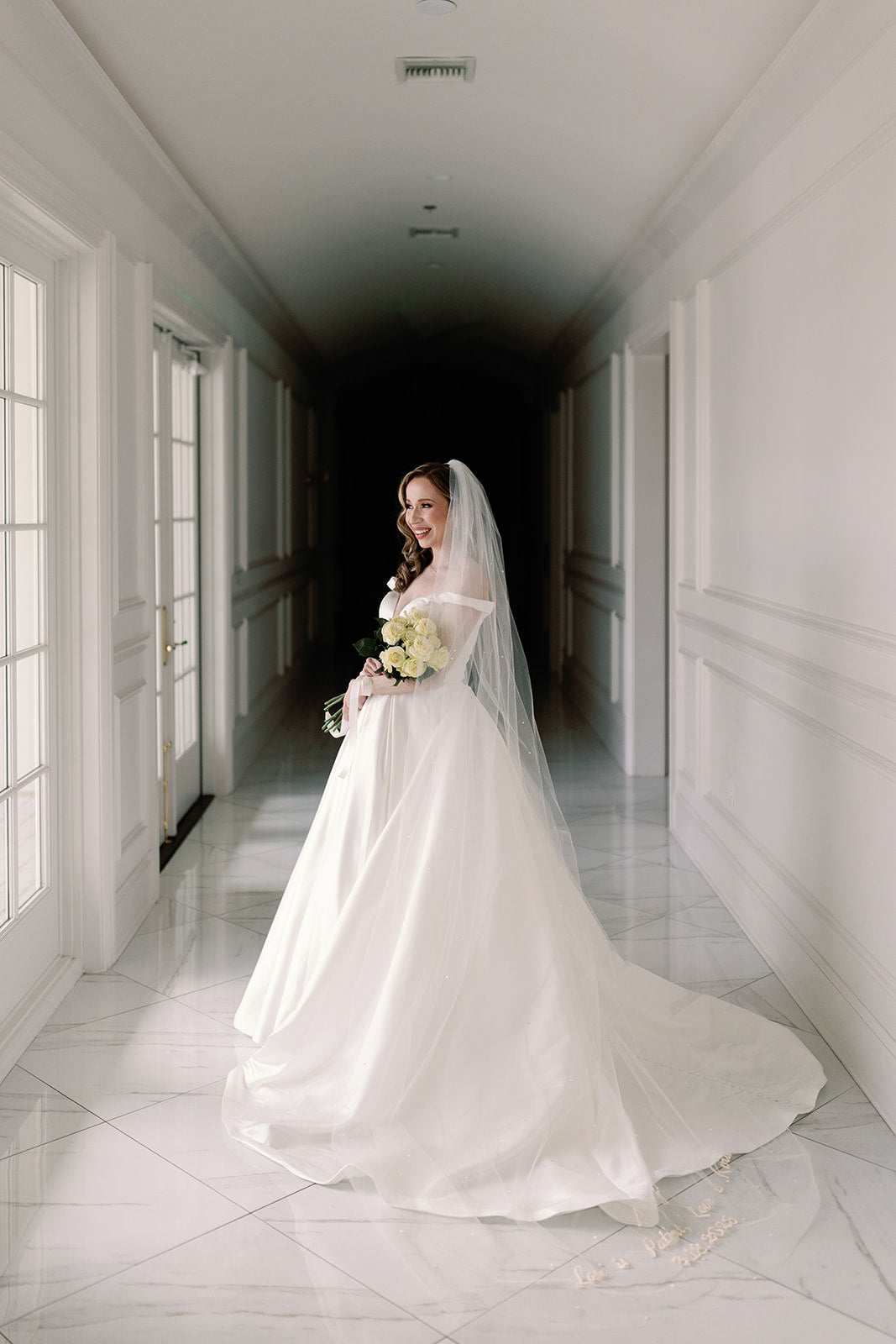 bride holding gorgeous yellow roses and wearing off the shoulder ballgown with pearl scattered wedding veil