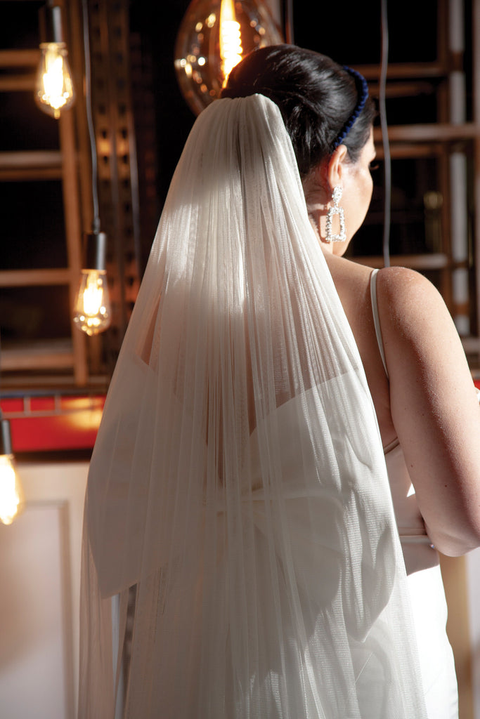 sleek bridal updo with blue headband and soft long chapel length wedding veil and hanging backlighting