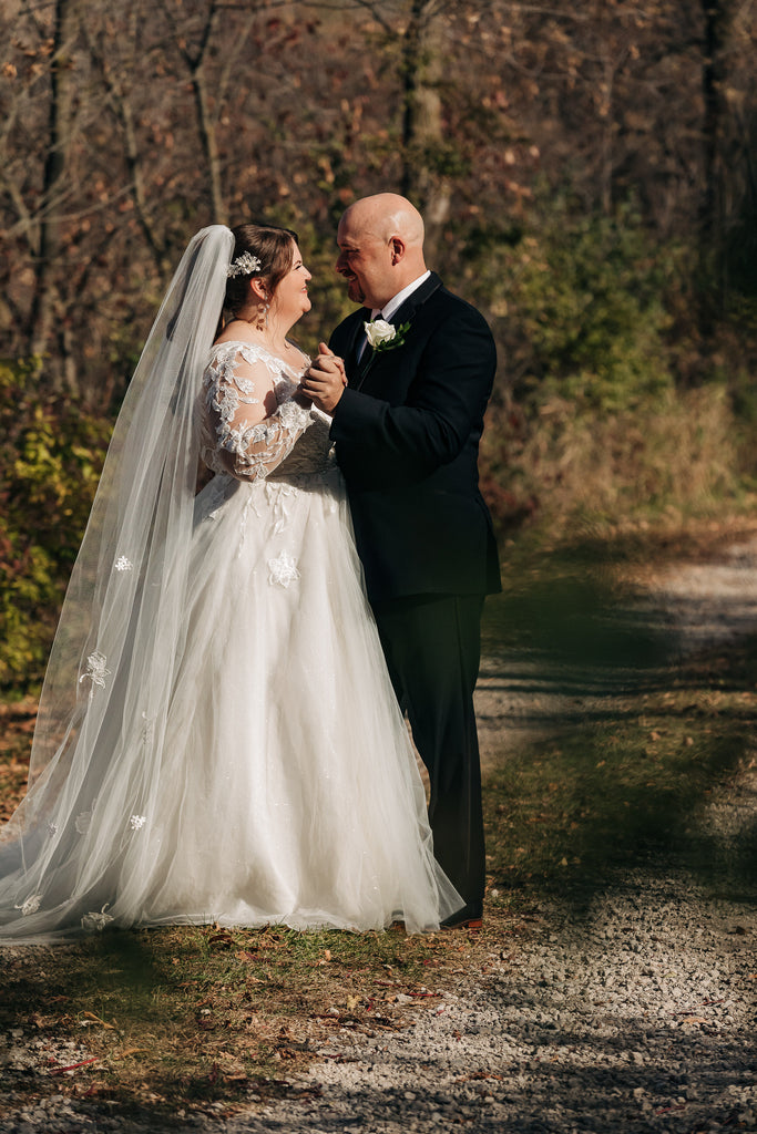 plus size bride in lace A Line dress and scattered flower chapel length bridal veil as she dances with groom