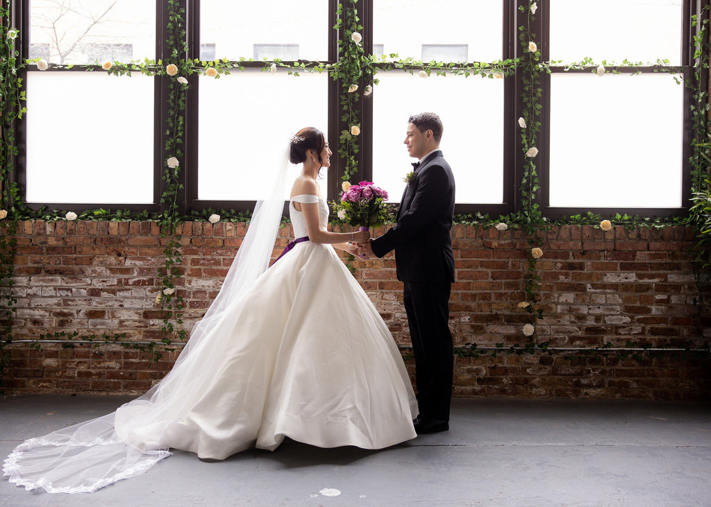 bride wearing ballgown and cathedral lace wedding veil with purple sash around waist