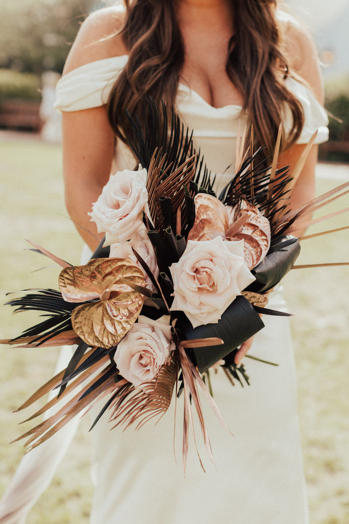 blush and rose gold bouquet in bride's hands on the beach
