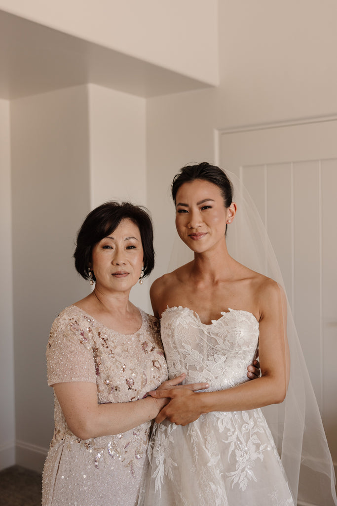 mother of the bride in blush gown with bride in sleek updo and blush wedding veil