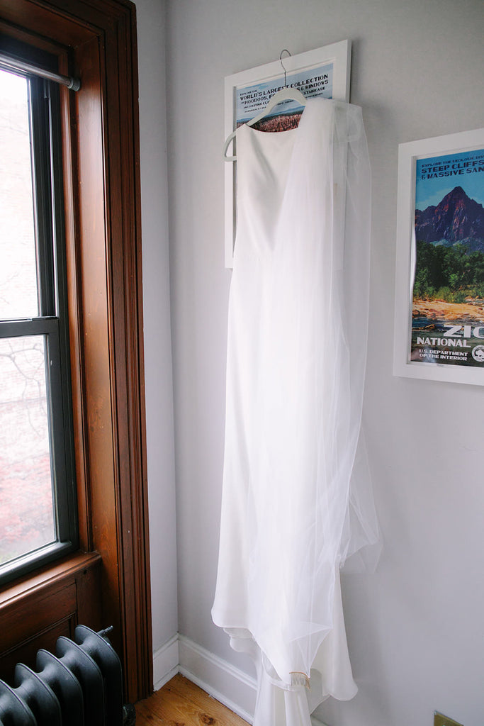 simple silk cathedral length wedding gown hanging on wall
