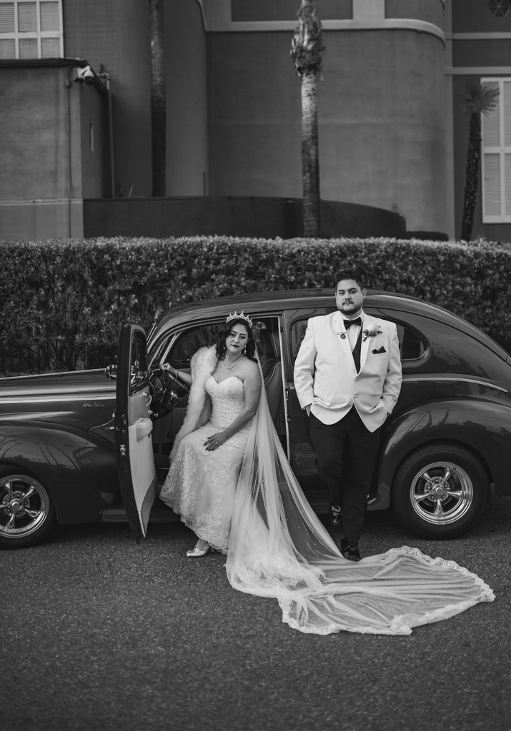 glamorous long bridal veil with lace on bride wearing tiara sitting in vintage car
