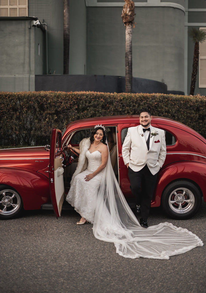 romantic Hollywood style California wedding with bride in gold tiara and long veil in red getaway car