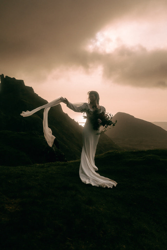 mikado modest a line bridal gown and long bridal veil wings for bride standing on Highlands in Scotland