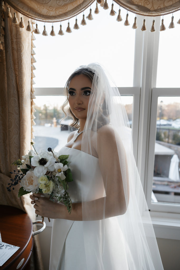 glam sophisticated and elegant bride in plain simple strapless silk gown and long bridal veil holding bouquet