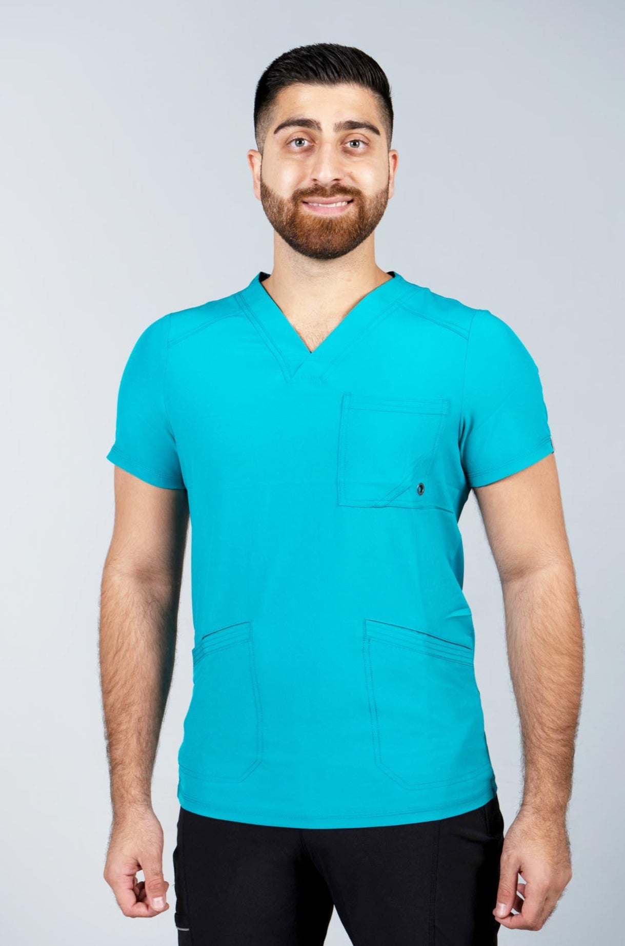 Male healthcare worker wearing teal scrub top and black scrub pants