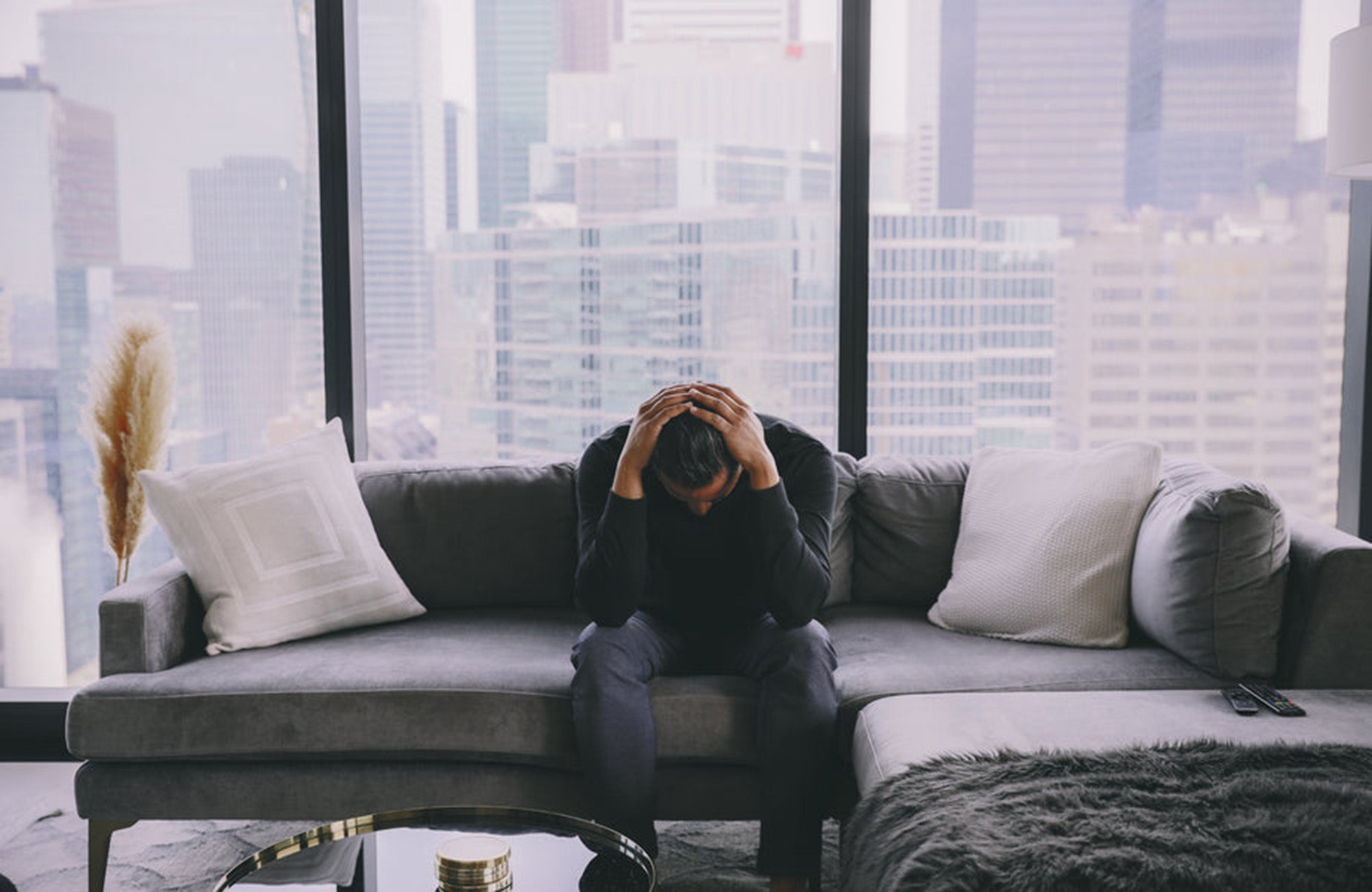 Grieving man in lounge room holding head in hands