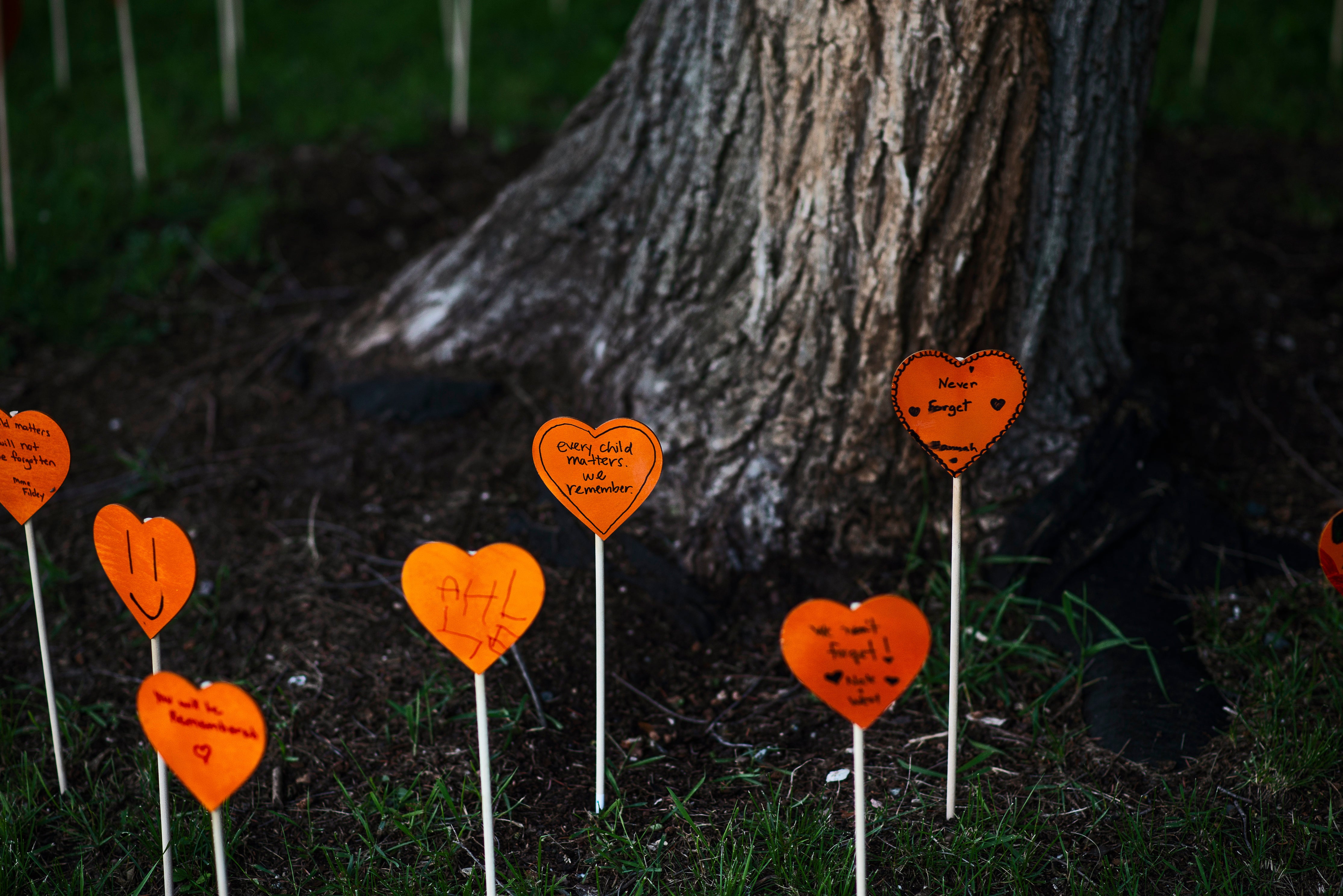 Orange paper love hearts at the base of a tree