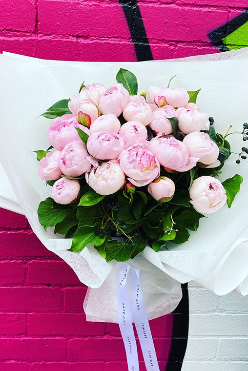 Peony bouquet with pink blooms in white paper