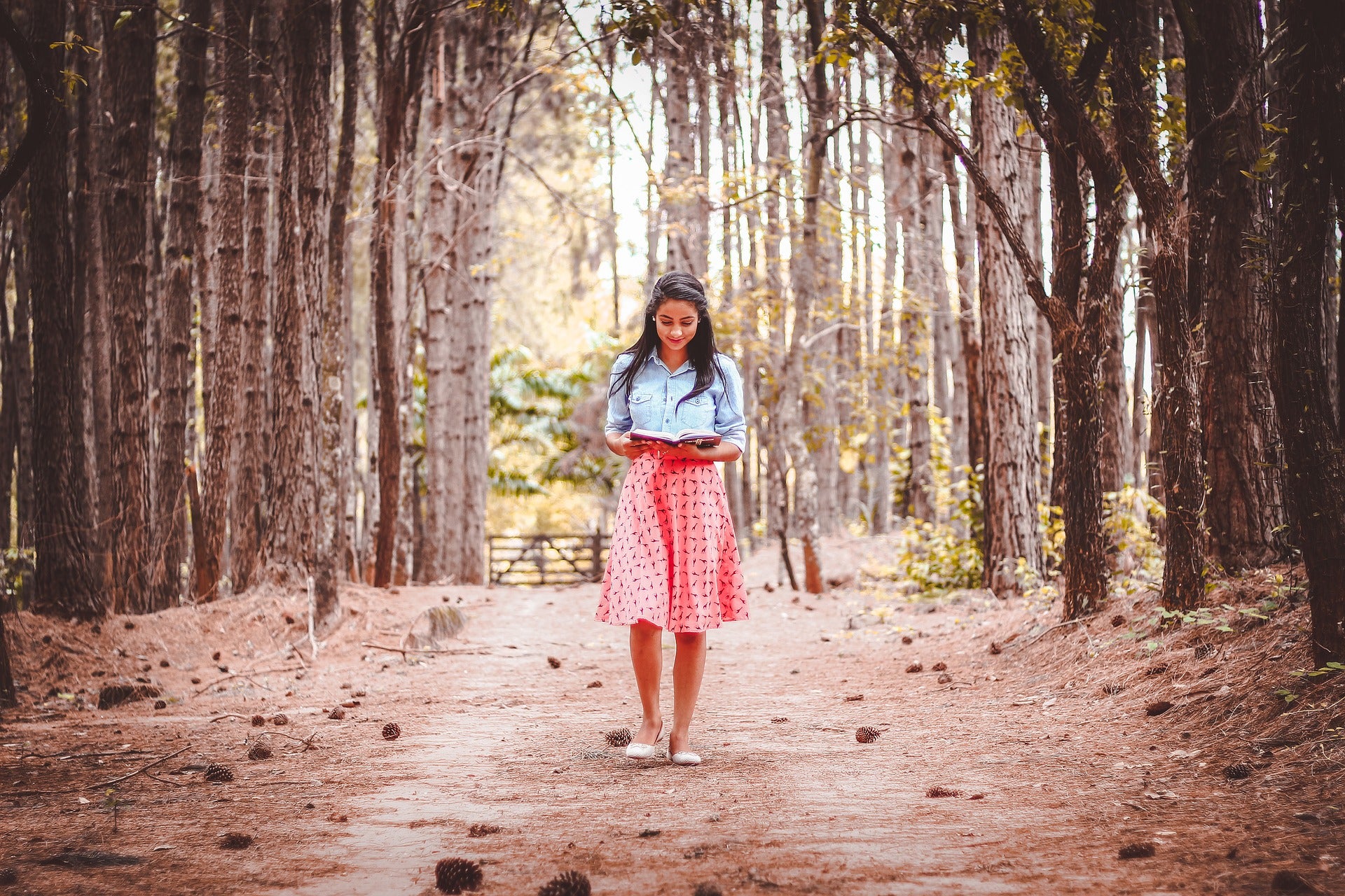 Girl walking in forest holding book
