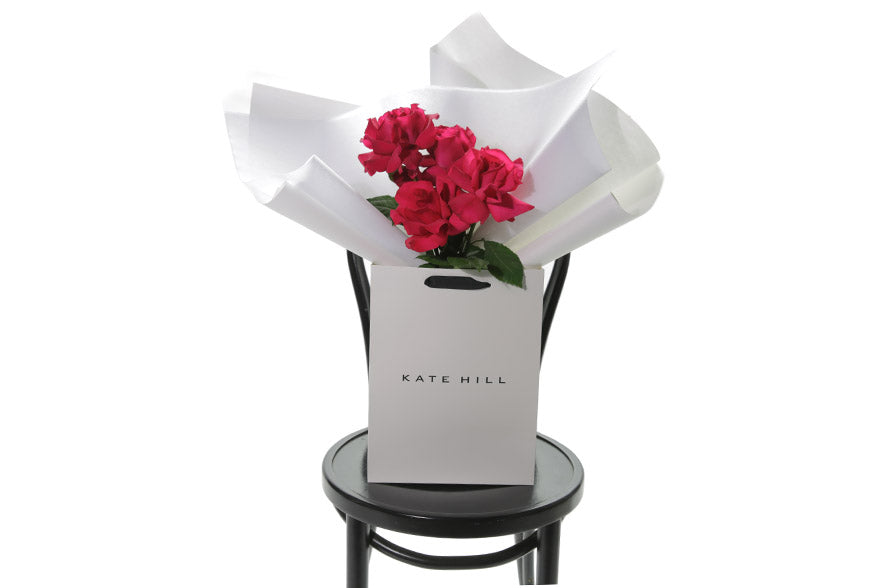 Product photo of red roses in white bag
