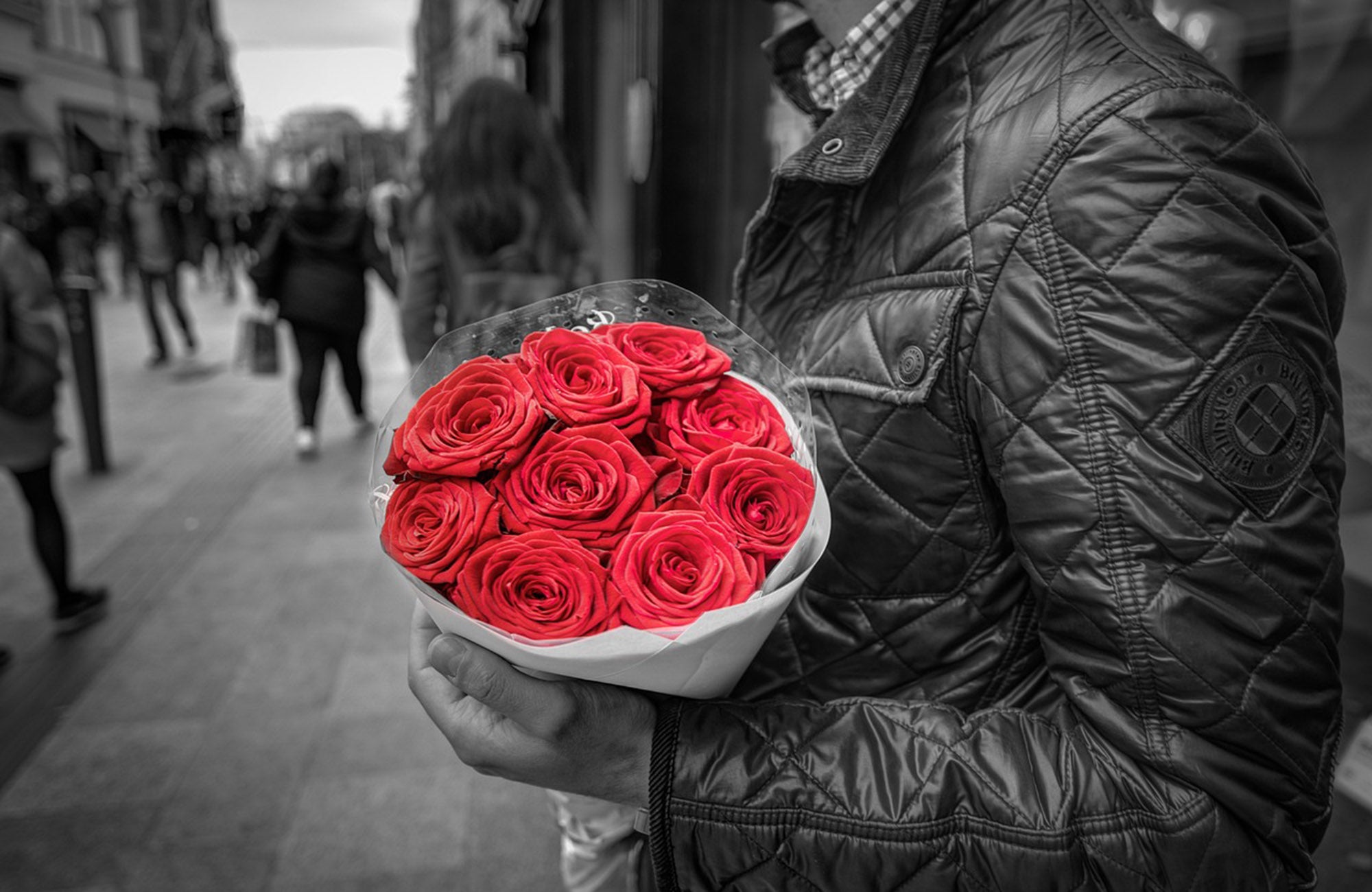 Man in leather jacket holding red roses for a romantic flower delivery