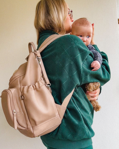 fourth trimester mum wears oioi oat nappy backpack and green tracksuit