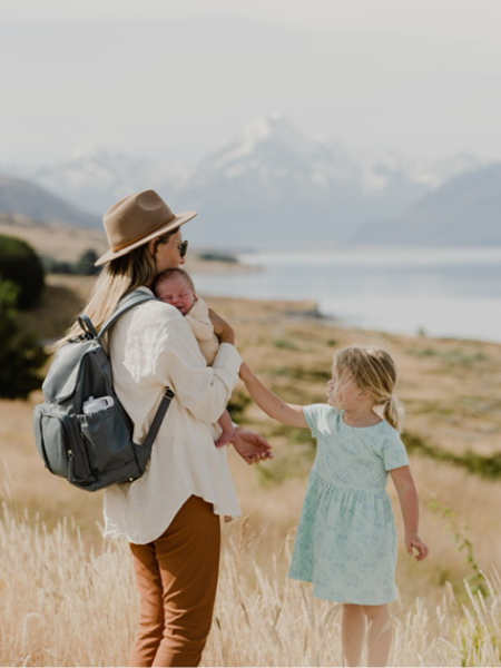 mother holds baby and toddler while on a road trip