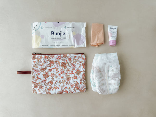 A wet bag filled with nappies, wipes, cream, and other nappy changing essentials, ready for on-the-go diaper changes.