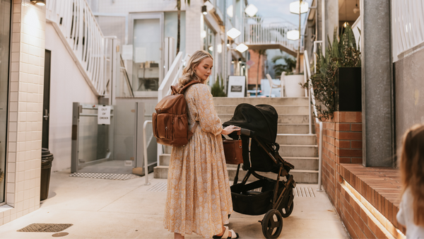 woman wearing oioi nappy backpack while pushing pram