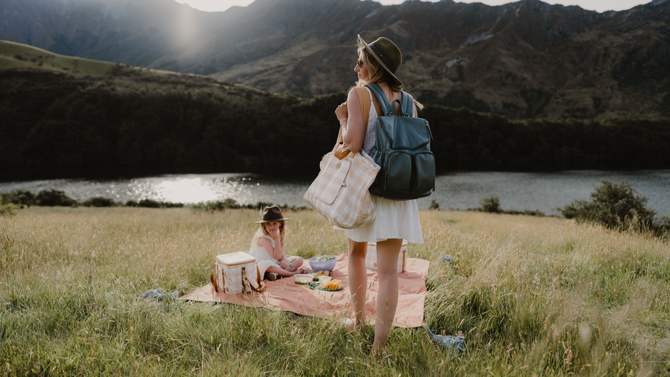 mother and daughter sitting enjoying a picnic by a lake in new zealand