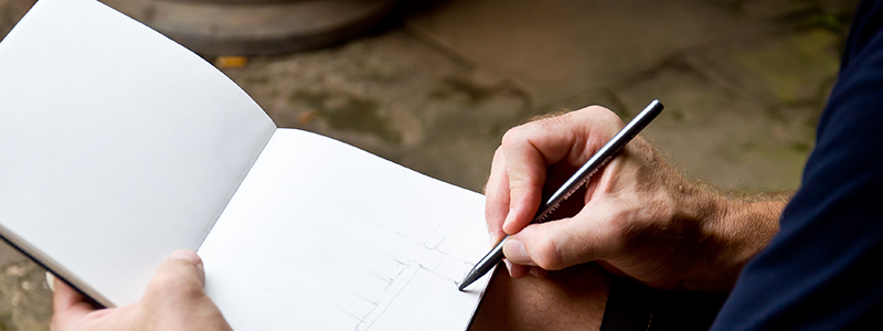 Gardener sketching out how they want to plan their backyard flower garden.