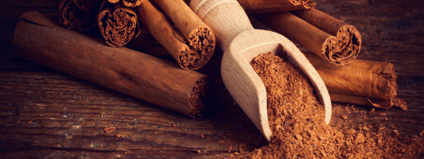 Ceylon Cinnamon sticks next to ground cinnamon pouring out of a wooden scoop