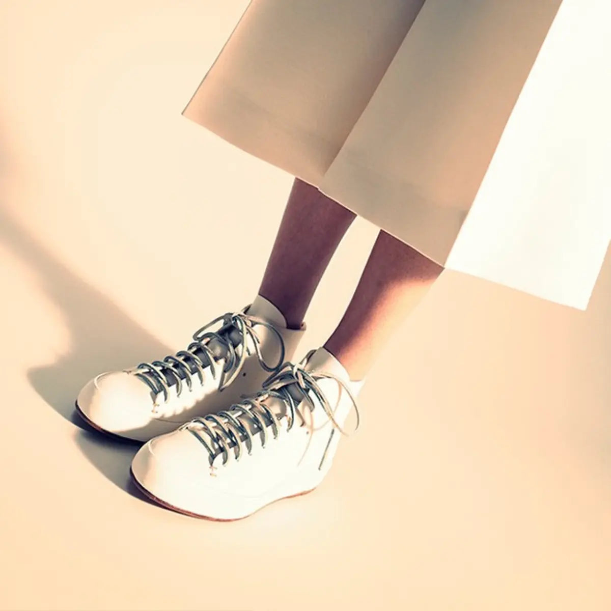 Sneaker cleaning tips highlighted with a model wearing spotless white high-top sneakers under a light skirt.