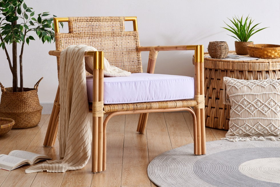 light and airy wicker chair with white cushion and beige throw. Set in a coastal themed room with macrame and potted plant decor.