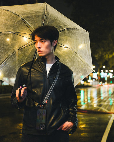 A man standing outdoors holding a black umbrella on a rainy day.