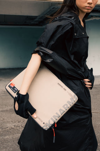 A woman in a black jacket carrying a laptop in its sleeve