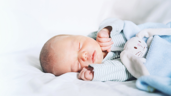 baby dressed in blue, sleeping with a bunny