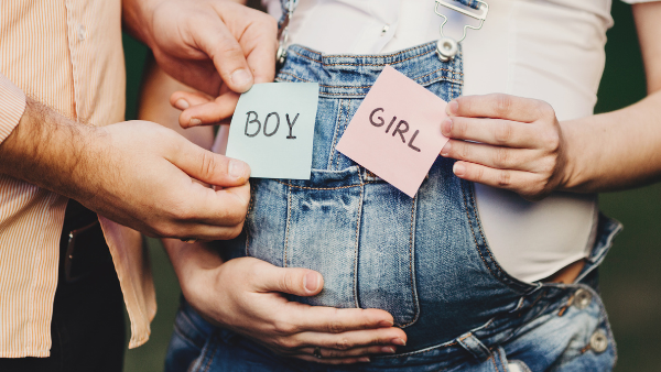 pregnant woman and partner holding boy or girl stickers on baby bump