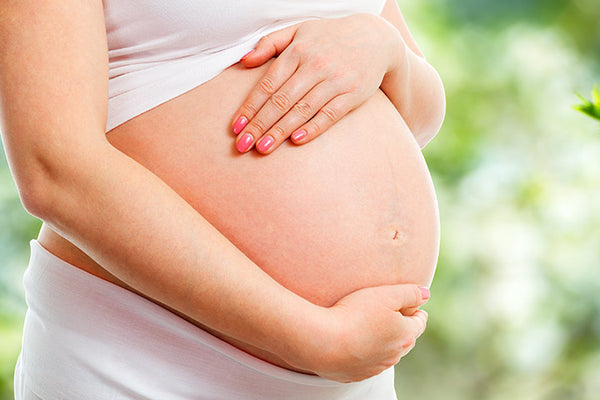 Pregnant woman with belly exposed holding her belly