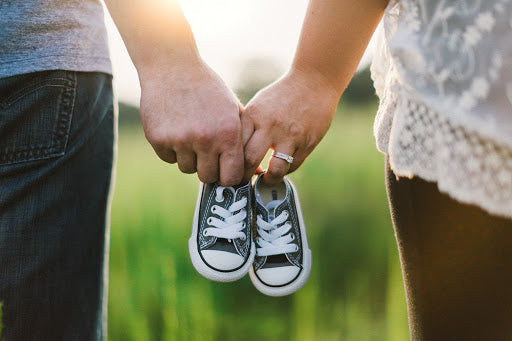 New parents expecting a baby - pregnant couple holding baby shoes