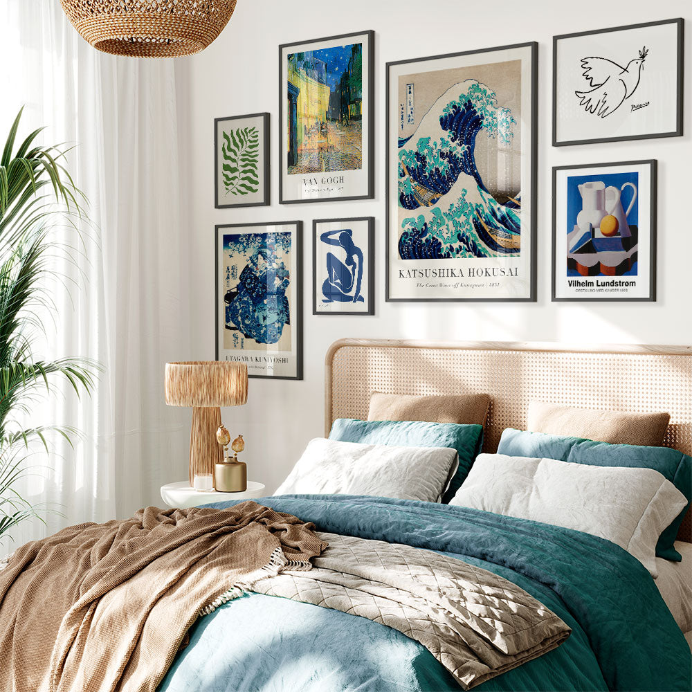 Large blue poster wall with unique art posters in beautiful black wooden frames hanging above a bed