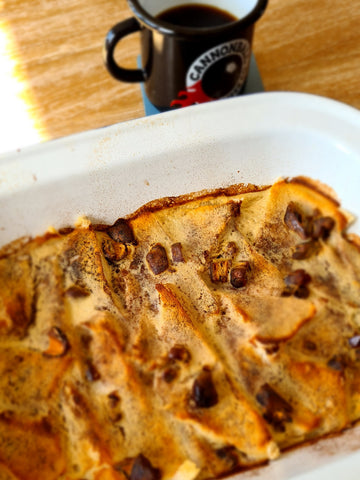 Tray of bread and butter pudding next to cup of black coffee