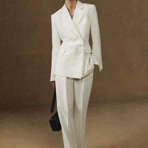 A woman wearing a structured white jacket and dress pants