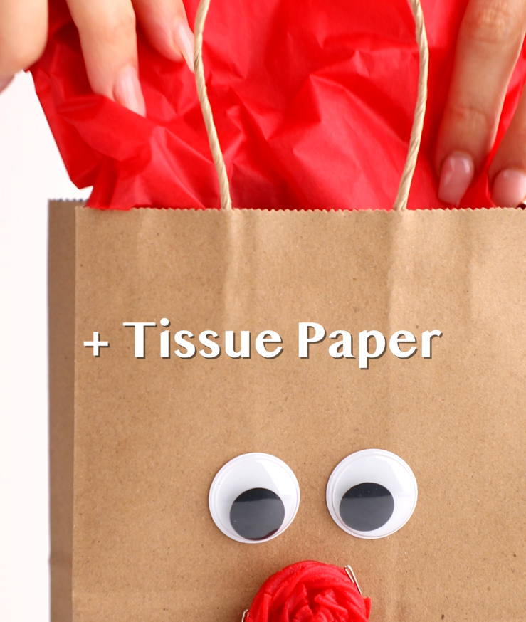 Red tissue paper being inserted into gift bag