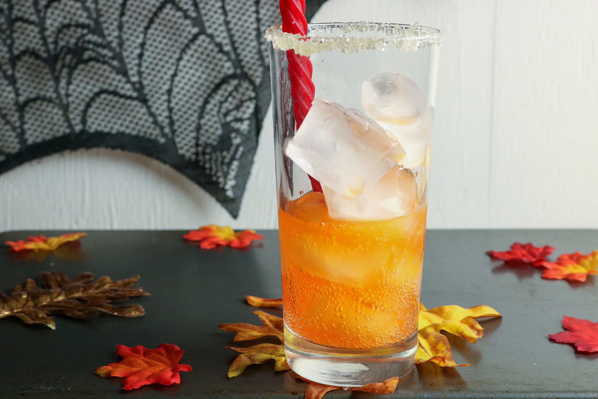 Glass with ice cubes, half filled with orange soda, sugar around the rim, and a Red Vines straw