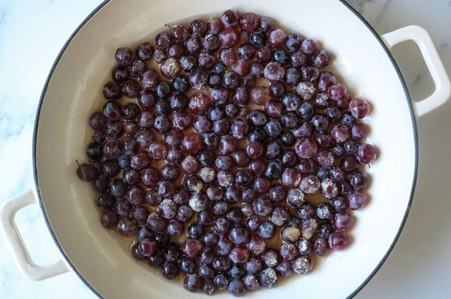 Grapes, sugar and water in a large white skillet