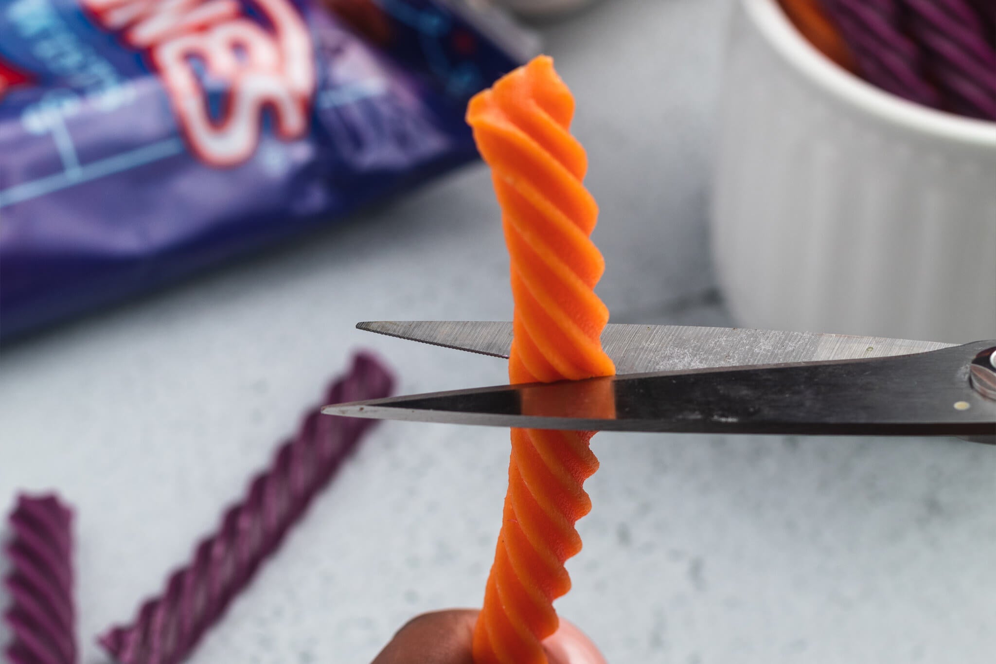 A scissors cutting Red Vines Licorice into pieces