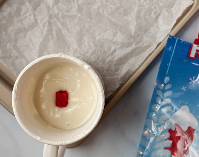 Red licorice piece being dipped into white chocolate