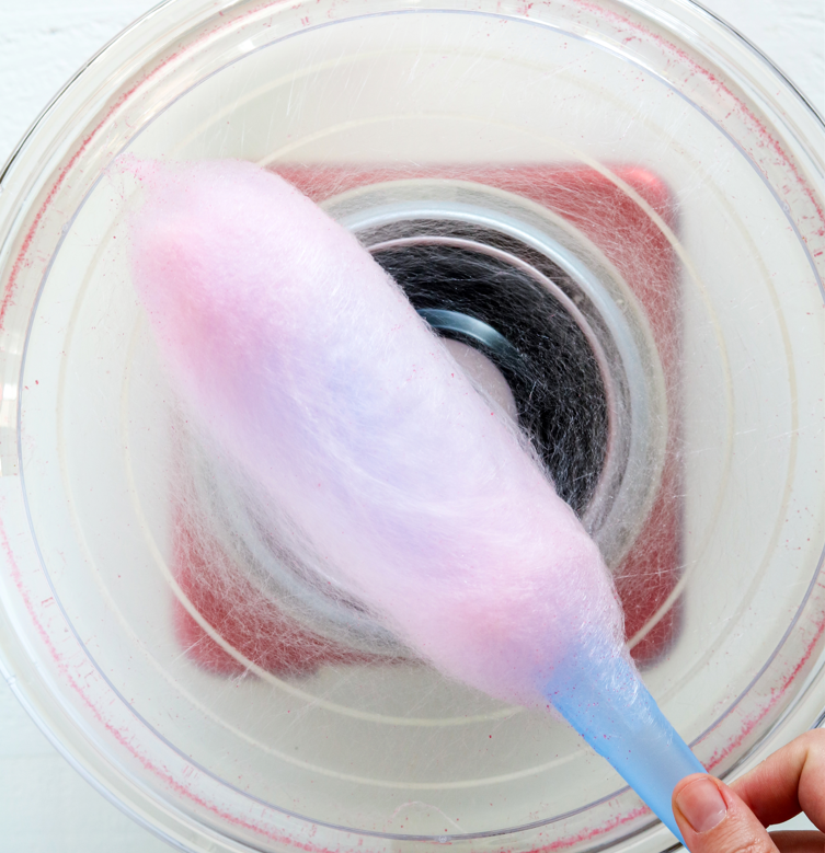 Pink cotton candy being spun onto the cone