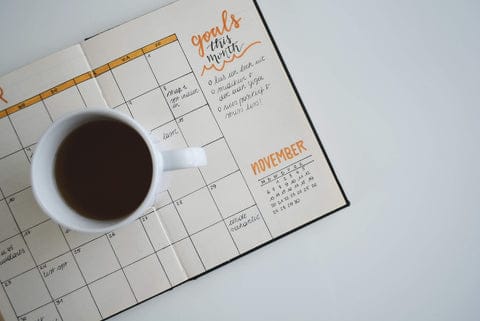 coffee next to monthly planner with goals written out