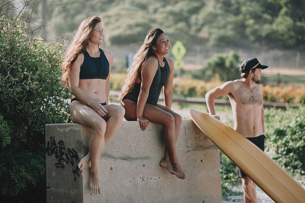 Two women and a man checking the surf dressed in Hakuna Surf Wear