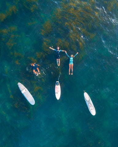 Drone image of people in water next to their surfboards